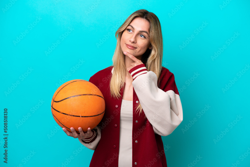 Young caucasian basketball player woman isolated on blue background and looking up