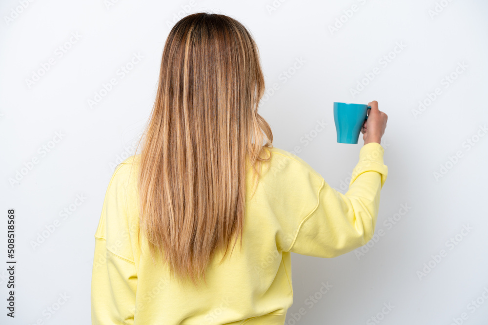 Young Uruguayan woman holding cup of coffee isolated on white background in back position