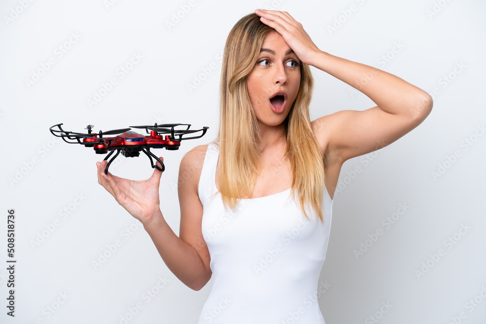Young Uruguayan woman holding a drone isolated on white background doing surprise gesture while looking to the side Young Uruguayan woman holding a drone isolated on white background doing surprise gesture while looking to the side
