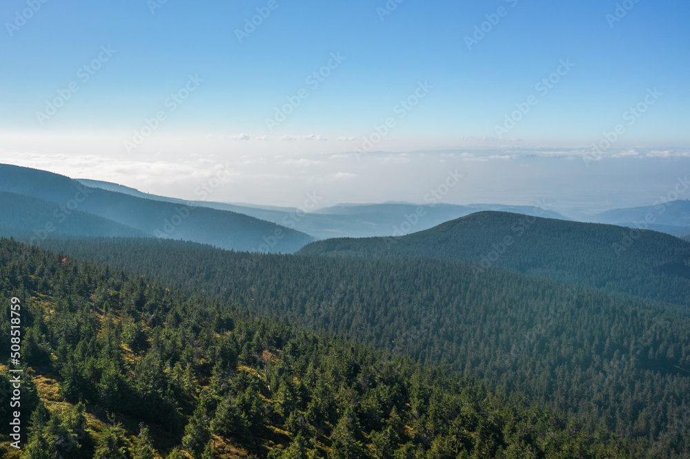 Aerial landscape of the green mountains. Clouds over the peaks in the background, clear blue sky. Aerial landscape of the green mountains. Clouds over the peaks in the background, clear blue sky.
