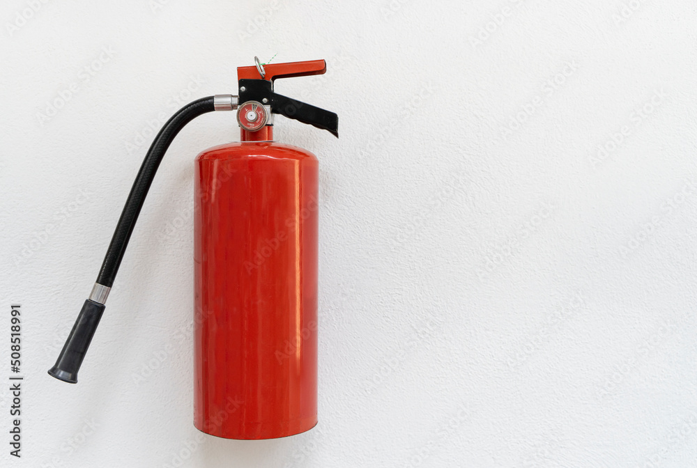 A red fire extinguisher on white wall, plain