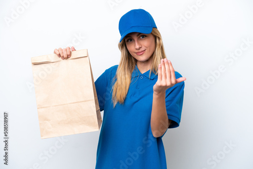 Young Uruguayan woman taking a bag of takeaway food isolated on white background inviting to come with hand. Happy that you came