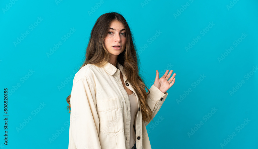 Young caucasian woman isolated on blue background making doubts gesture Young caucasian woman isolated on blue background making doubts gesture
