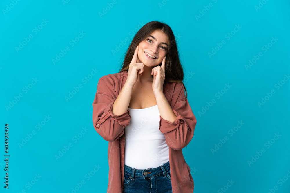 Young caucasian woman isolated on blue background smiling with a happy and pleasant expression Young caucasian woman isolated on blue background smiling with a happy and pleasant expression