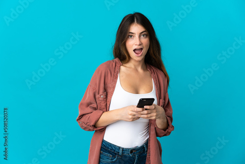 Young caucasian woman isolated on blue background surprised and sending a message