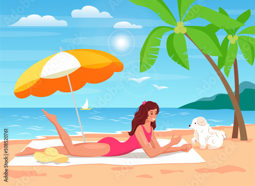 Woman is sunbathing on a towel and playing with a dog under a summer umbrella 