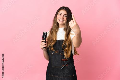 Young hairdresser woman isolated on pink background doing coming gesture