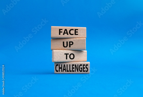Face up to challenges symbol. Wooden blocks with words Face up to challenges. Beautiful blue background. Business and Face up to challenges concept. Copy space.
