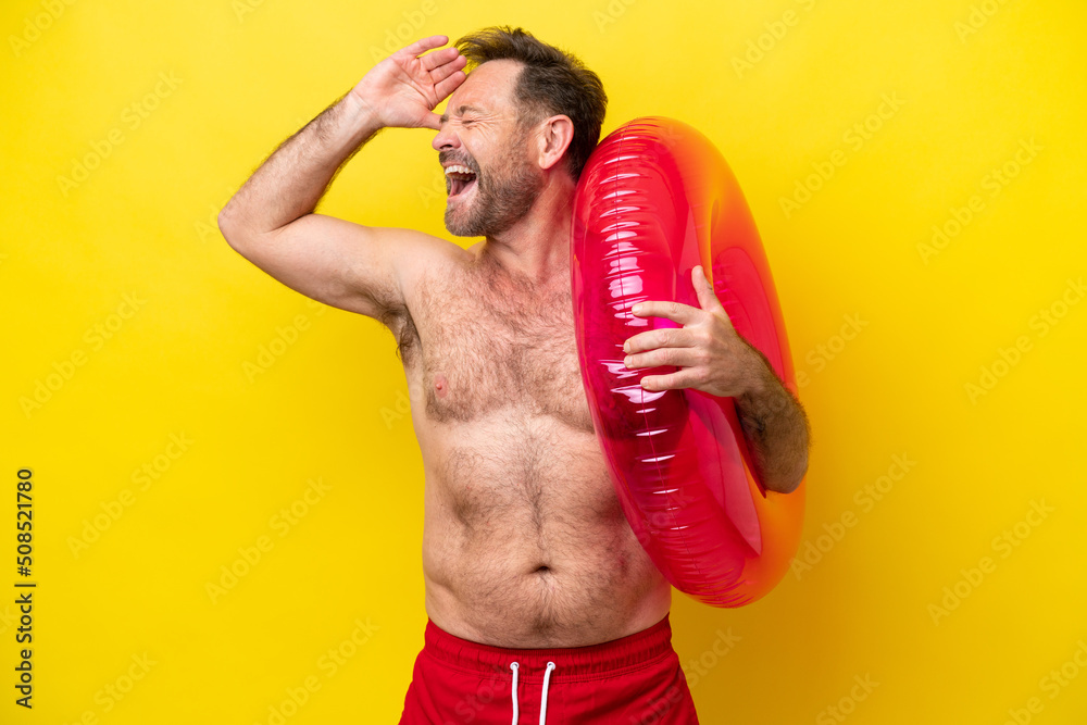 Middle age caucasian man holding inflatable donut isolated on yellow background smiling a lot
