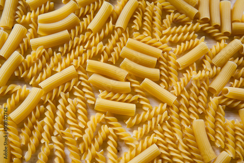Background from macaroni fusilli and maccheroni rigati, top view. Raw pasta as background, close-up. Italian wheat pasta for poster, calendar, post, screensaver, wallpaper, banner, cover, website