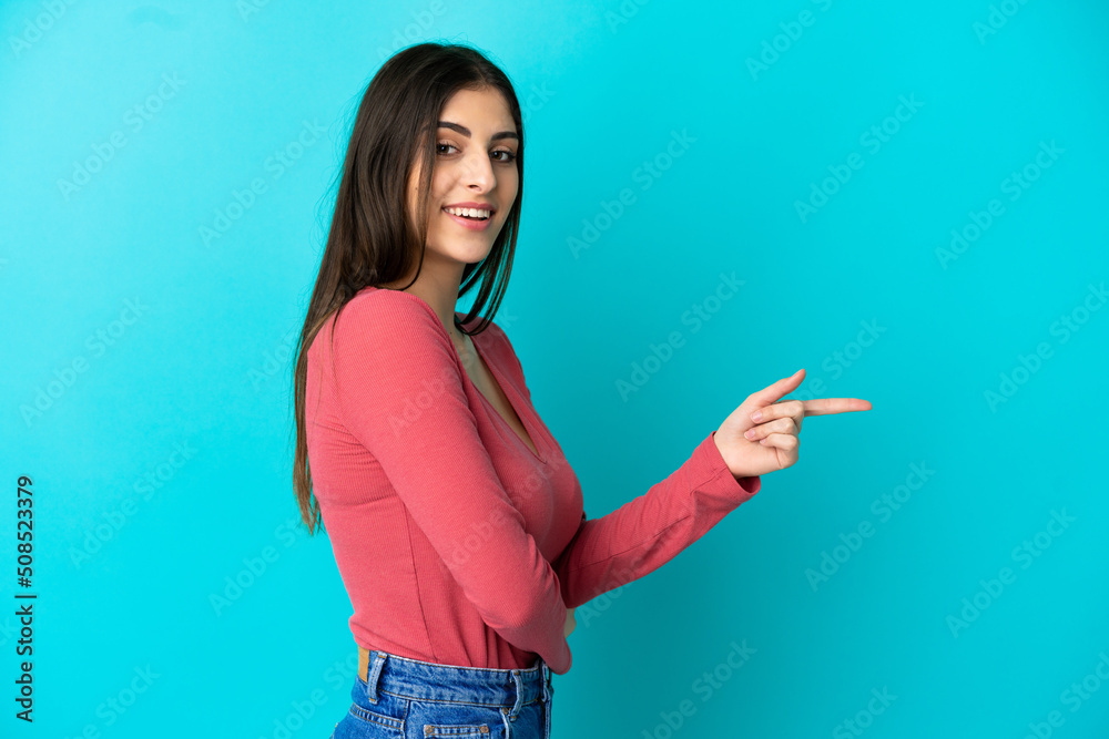 Young caucasian woman isolated on blue background pointing finger to the side Young caucasian woman isolated on blue background pointing finger to the side