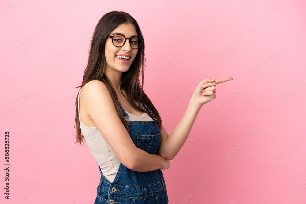Young caucasian woman isolated on pink background pointing finger to the side Young caucasian woman isolated on pink background pointing finger to the side