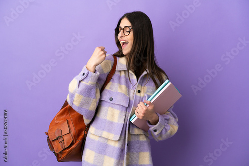 Young student woman isolated on purple background celebrating a victory