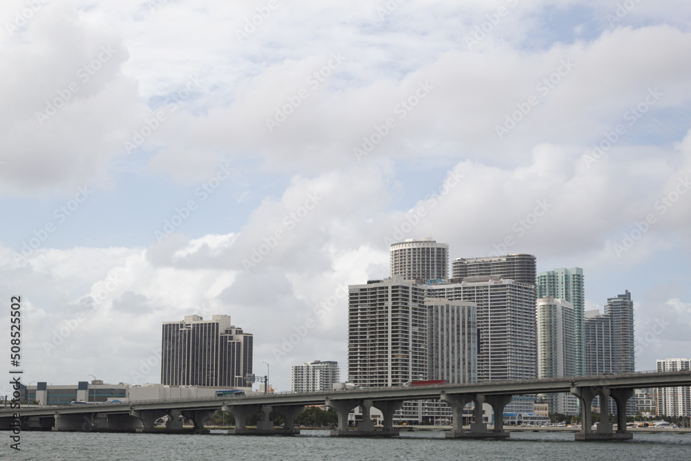 Some buildings and a bridge in Miami, Florida with a sky full of clouds in the background