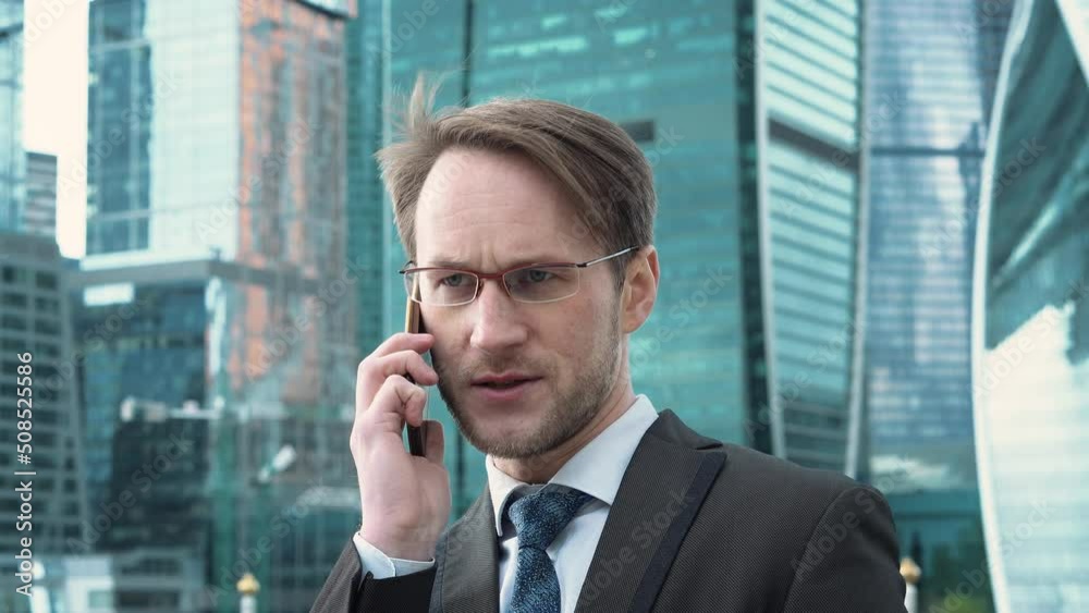 Businessman in eyeglasses talking on the phone. Moscow city, International Business Center on background Businessman in eyeglasses talking on the phone. Moscow city, International Business Center on background