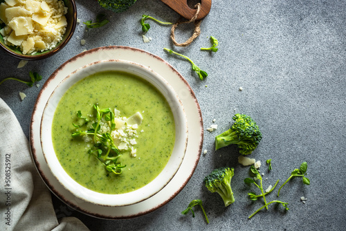 Green soup. Broccoli cream soup with parmesan and microgreen. Healthy vegan dish. Top view at stone table. photo