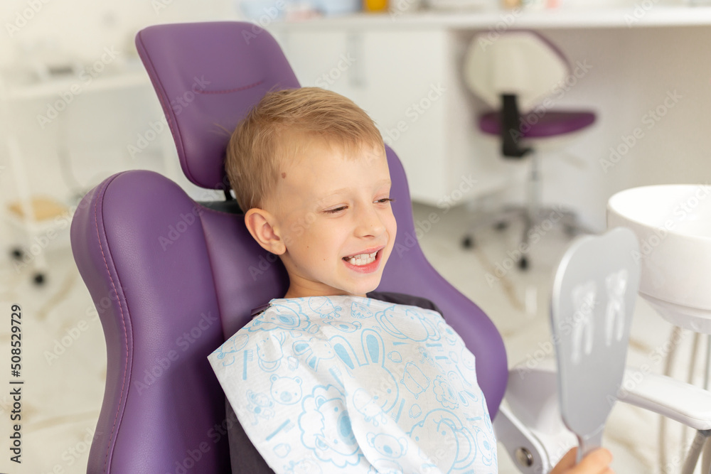 Cute little boy sitting on dental chair and smiling Cute little boy sitting on dental chair and smiling