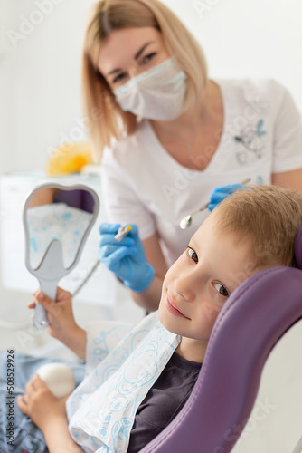 Cute little boy sitting on dental chair and having dental treatment