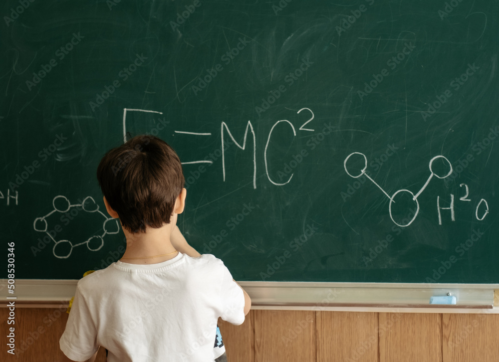 The concept of a simple letter of a child at school. The first grader writes on the blackboard. Development of a genius child