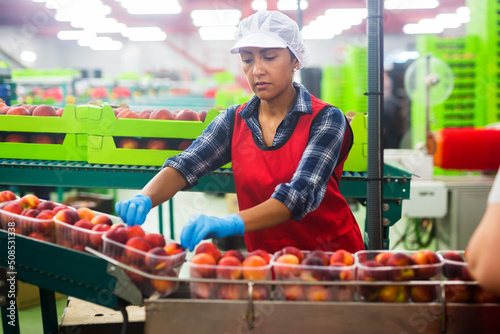 Portrait of confident latina woman working at sorting department at fruits industrial production facility