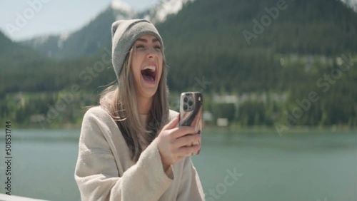 Blond woman wearing a beenie FaceTime outdoors on a cruiseship in Alaska