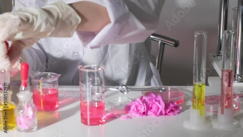 A gloved hand holds a pipettу over a petri dish in an up-to-date perfume laboratory. Background blurred photo