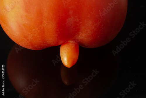 Mutated tomato on a dark background. Male penis size concept