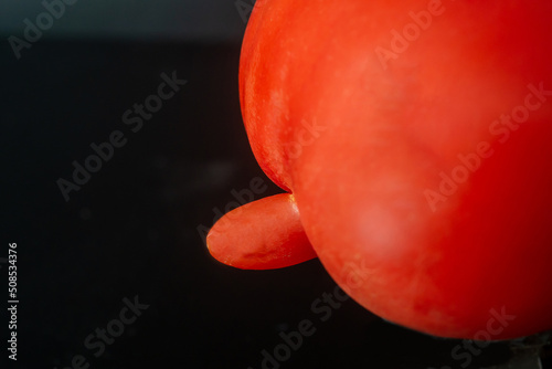 Mutated tomato on a dark background. Male penis size concept