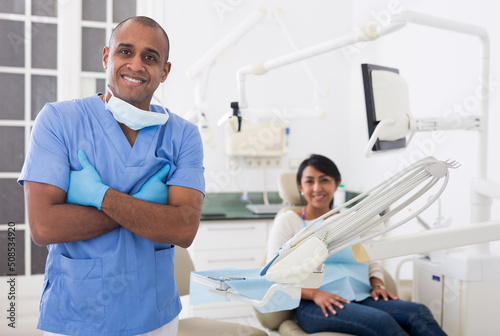 Portrait of positive dentist in dental office on the background of patient
