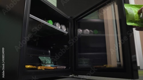 Hand takes a snack from minibar at a hotel