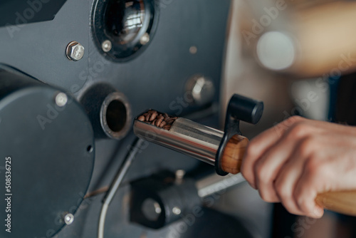 Close up of business owner hands operating modern coffee bean roasting machine