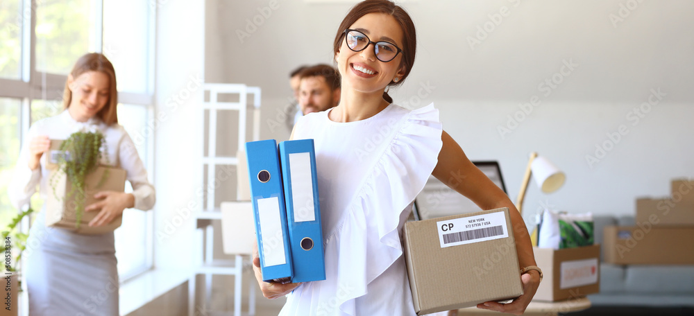 Beautiful businesswoman with folders and box in office on moving day Beautiful businesswoman with folders and box in office on moving day