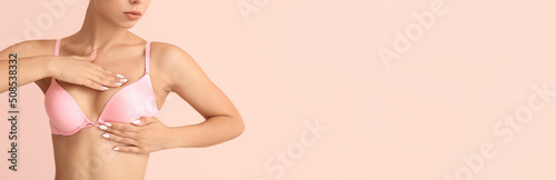 Young woman checking her breast on color background with space for text. Cancer awareness concept