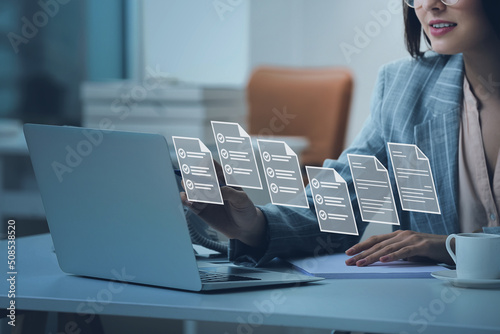 Young secretary with laptop and digital files on virtual screen in office photo