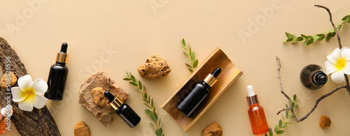 Composition with bottles of natural essential oils on beige background, top view