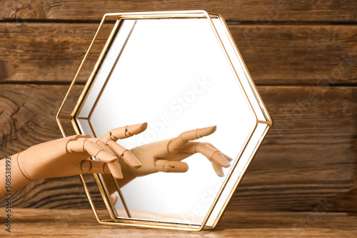 Decorative hand with mirror on wooden background