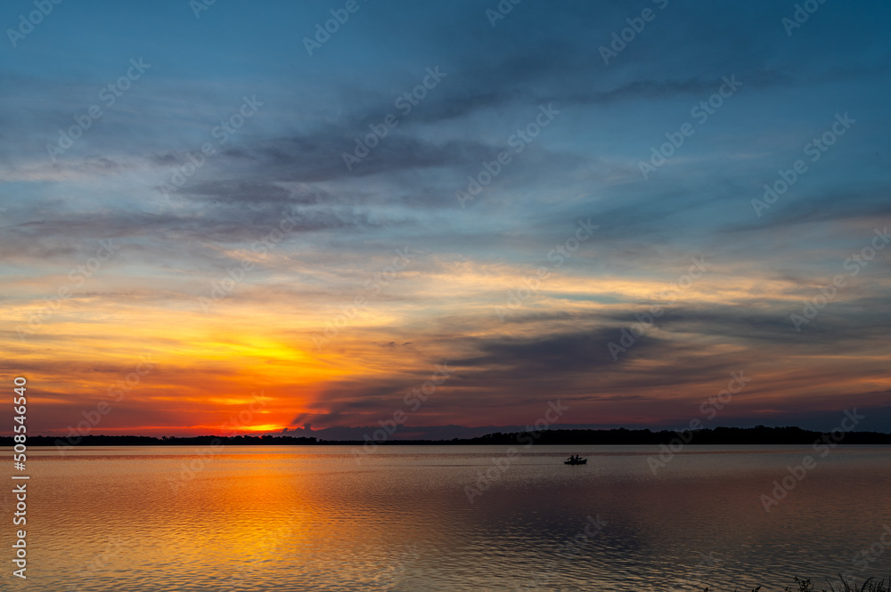 Fishing Boat at Sunset with Colorful Reflections on Lake Fishing Boat at Sunset with Colorful Reflections on Lake