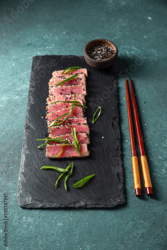 Japanese food. Tuna tataki. Raw tuna sashimi searahi con cesamo on black board. photo