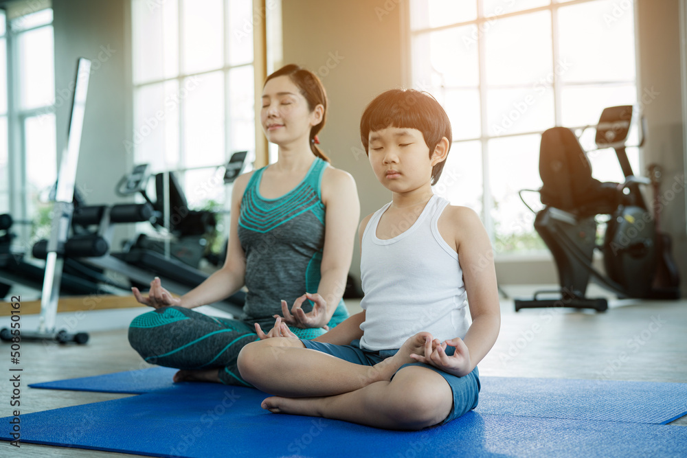 Mother with a little son having fun together and doing sport yoga in the fitness room. Mum playing with son. Mother with a little son having fun together and doing sport yoga in the fitness room. Mum playing with son.