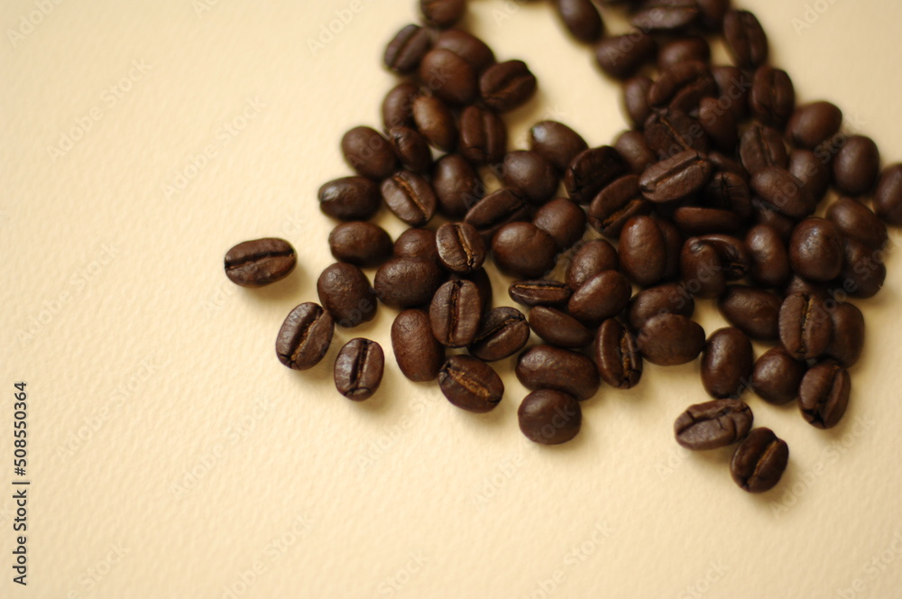 Naklejka premium マイルドで香り高いコーヒー豆が生成りの背景に。カフェで珈琲で一服。