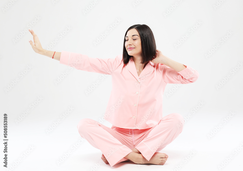Young asian woman in pink pajama sitting on the floor and stretching Young asian woman in pink pajama sitting on the floor and stretching