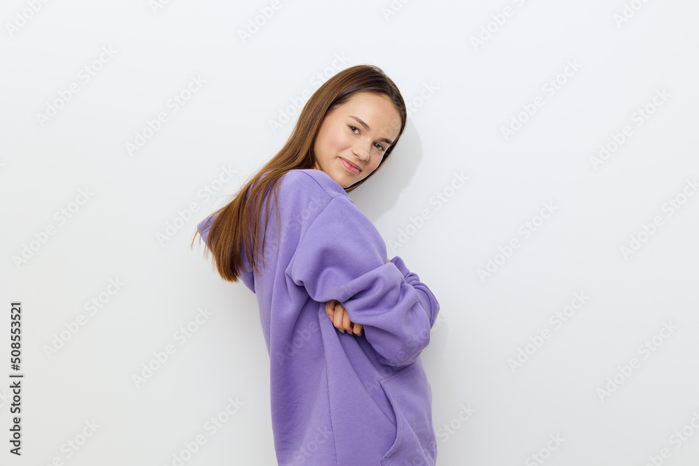 a delightful woman stands on a white background in a purple tracksuit stands half a turn and hugs herself, clutching a hoodie a delightful woman stands on a white background in a purple tracksuit stands half a turn and hugs herself, clutching a hoodie