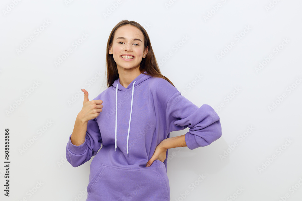 an enthusiastic beautiful woman stands on a white background in a purple tracksuit happily shows the class, putting her other hand on her hip an enthusiastic beautiful woman stands on a white background in a purple tracksuit happily shows the class, putting her other hand on her hip