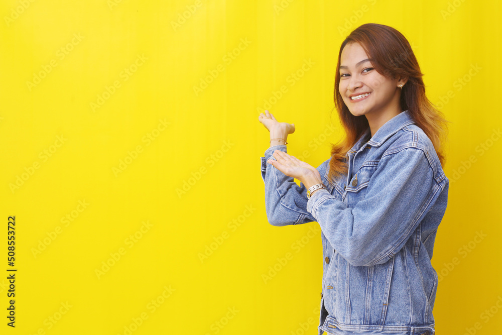 Happy asian young woman showing something sideways. Isolated on yellow background with copyspace Happy asian young woman showing something sideways. Isolated on yellow background with copyspace