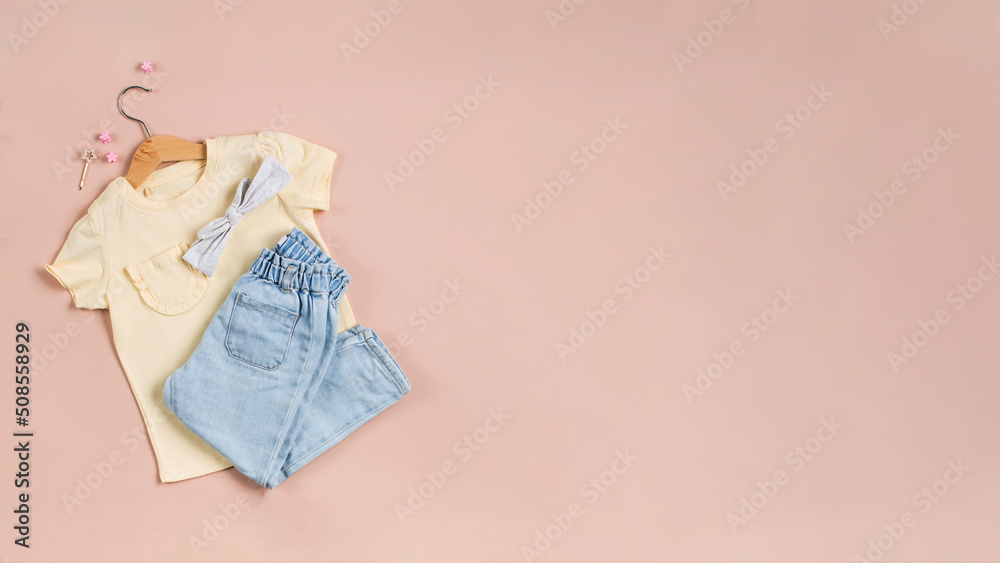 Childish image with jeans, a yellow t-shirt and accessories on a pink background. Copy space. Childish image with jeans, a yellow t-shirt and accessories on a pink background. Copy space.