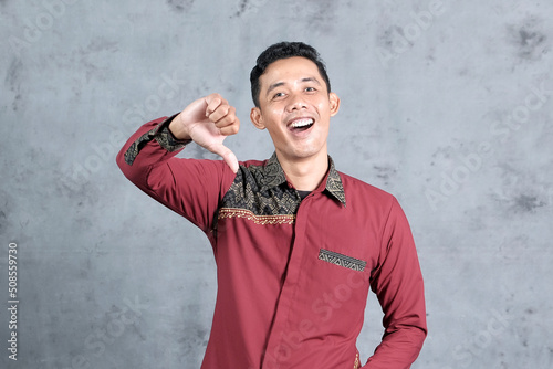 Obraz na plátně An Asian man showing condescending expressions and gestures on a gray studio bac