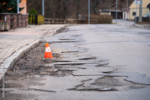 Foto Damaged asphalt pavement road with potholes and traffic cone
