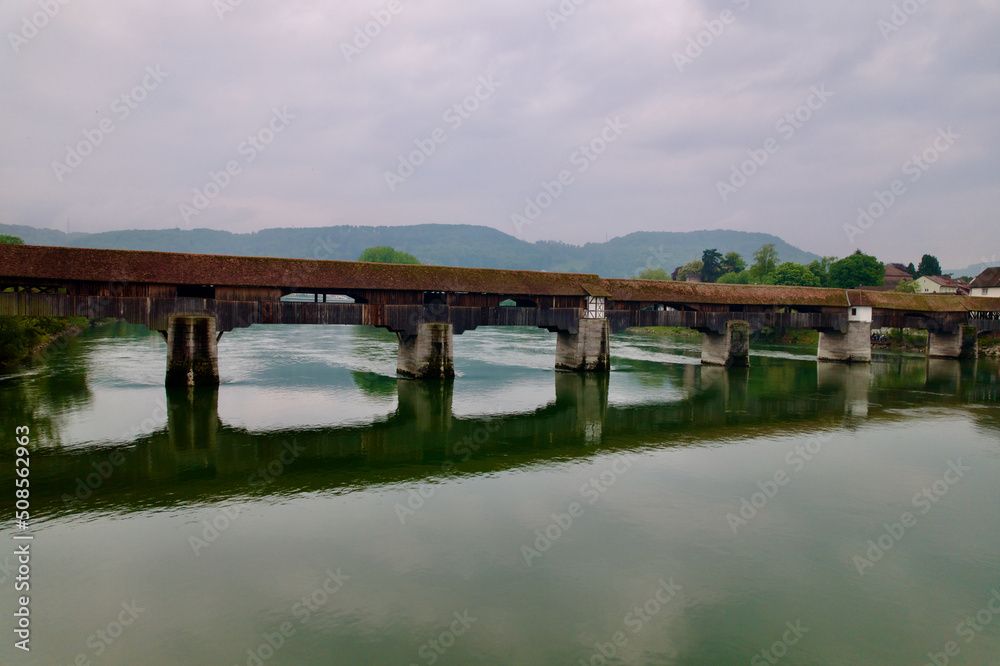 Fototapeta premium Covered wooden bridge over the Rhine River at Stein, Canton Aargau, and Bad Säckingen, Baden-Württemberg, on a cloudy spring day. Photo taken May 6th, 2022, Stein, Switzerland.