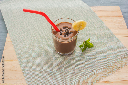 Chocolate Banana Shake Topping Sprinkled with Chocolate Chips, Banana and Mint Leaves with Straw on Cloth