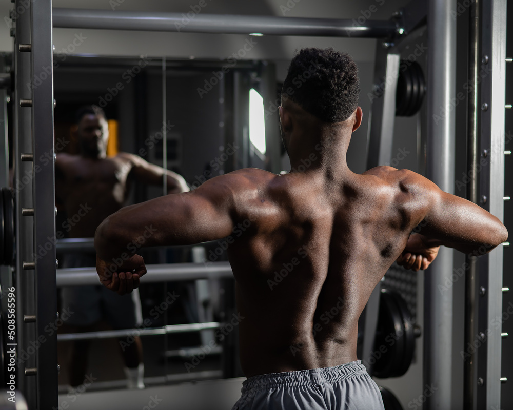 Handsome afro american man posing showing back muscles in gym. Handsome afro american man posing showing back muscles in gym.